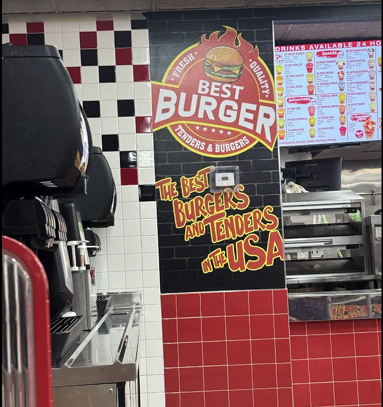 The Best Burger interior wall painted in gold letters: 'The Best Burgers and Tenders in the USA,' above the counter and menu board.