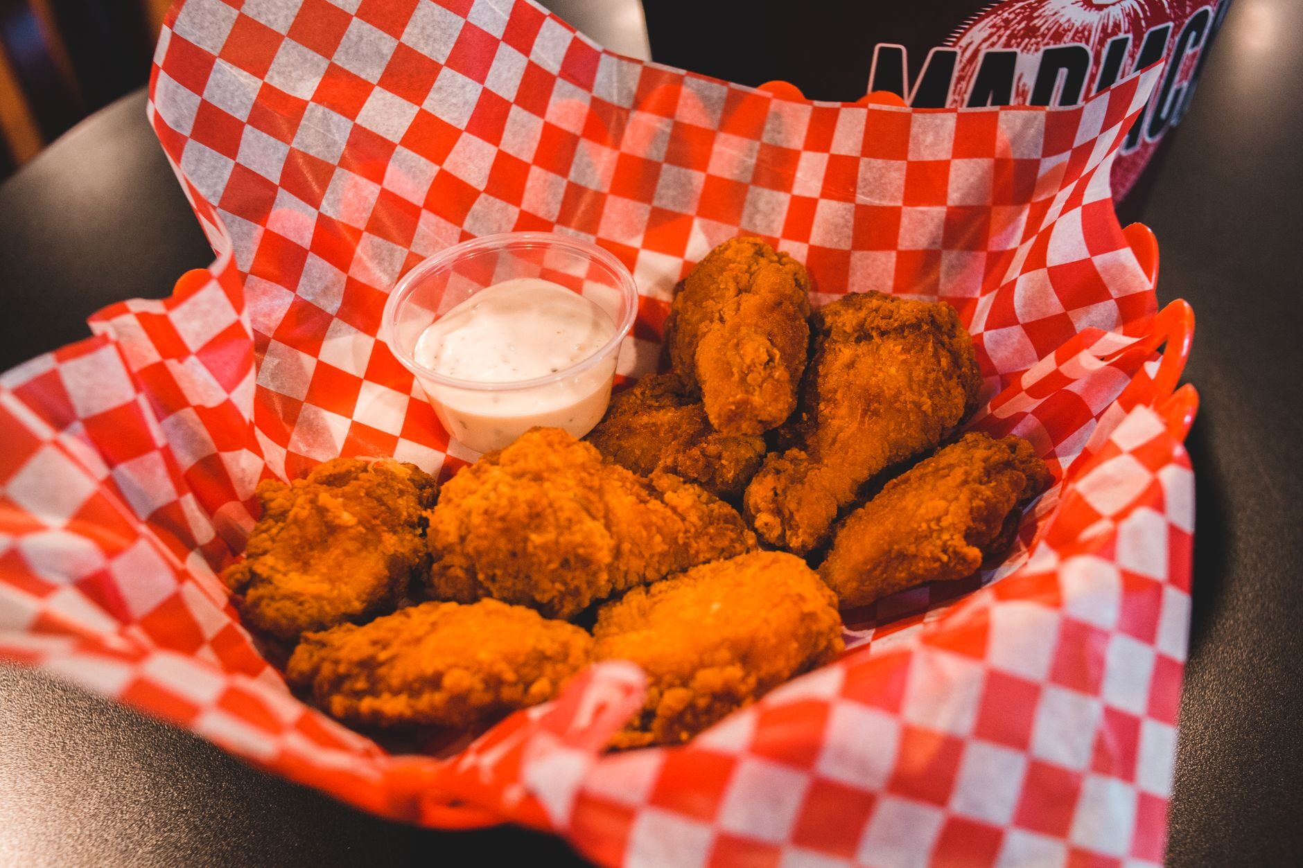 Crispy fried chicken tenders in a red-and-white checkered paper basket.